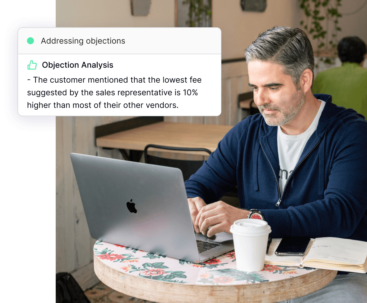 A man focused on his laptop at a table, accompanied by a laptop and a coffee cup, enhancing productivity and gaining a competitive advantage.