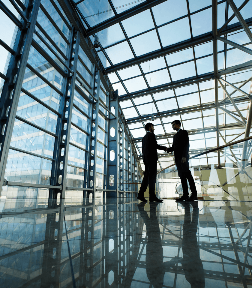 Two professionals sealing a deal in a modern glass office building, leveraging meeting analytics to drive revenue growth.