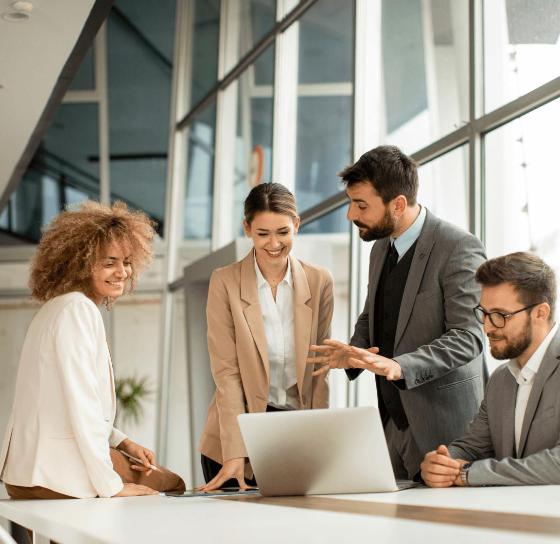 A diverse group of individuals intently gathered around a laptop, collaborating on setting and measuring KPIs for AI platforms.