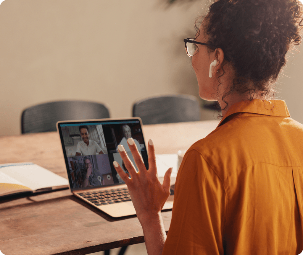 People huddled around a table, working on laptops and discussing Spiky's AI tool streamlining customer success tasks for effortless wins.