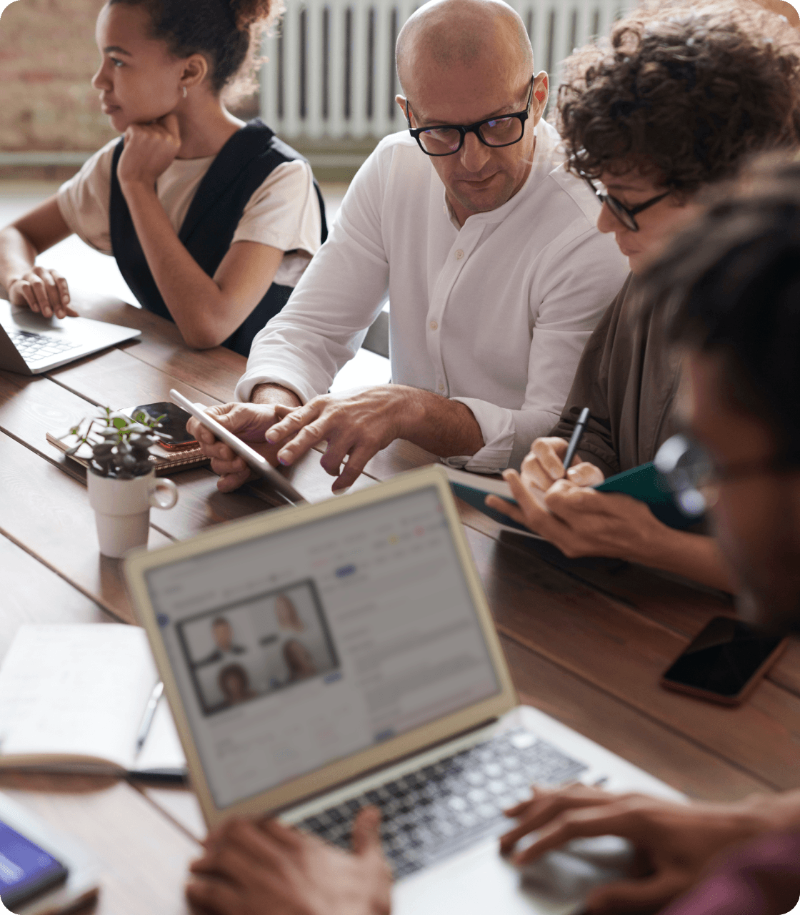 A group of people sitting at a table with laptops, collaborating on tasks and utilizing AI-powered tools for sales team success.