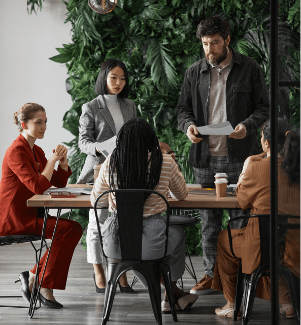 Professionals discussing revenue intelligence strategies at an office table, preparing for a comprehensive Spiky vs. Avoma comparison analysis.