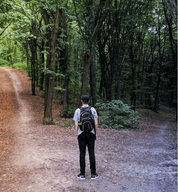 A backpack-clad man stands on a woodland path, inviting you to explore Spiky vs. Otter's revenue intelligence methodology.