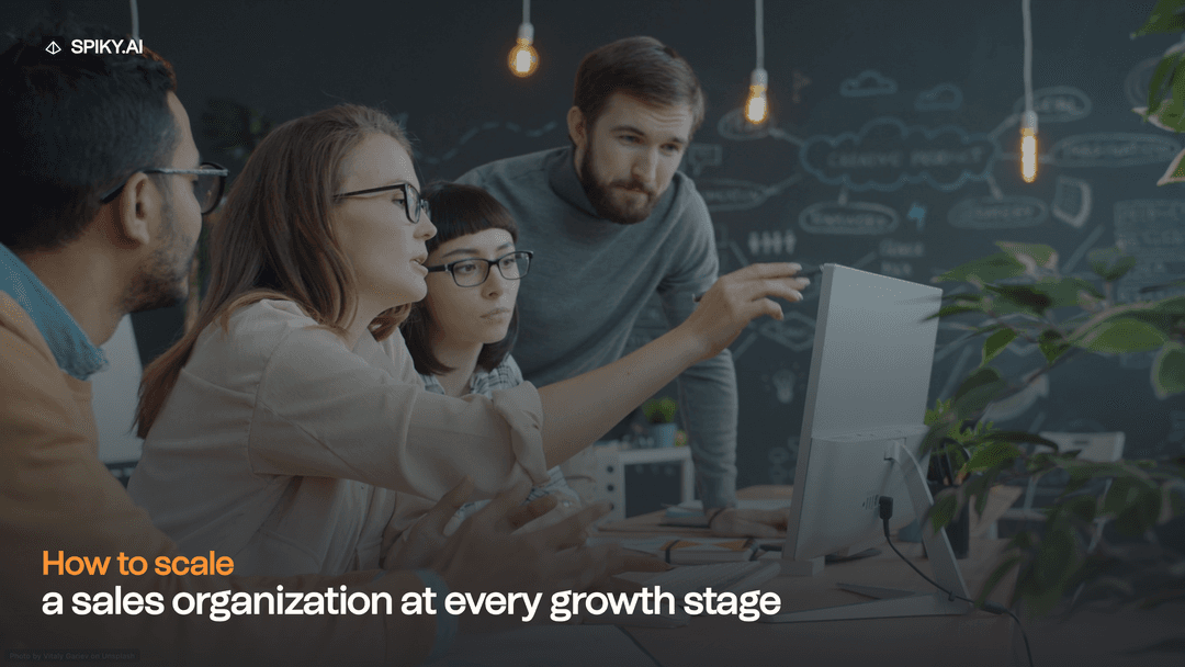 A diverse sales team collaborates around a desktop computer in a modern office, with chalkboard sketches and text about scaling growth.