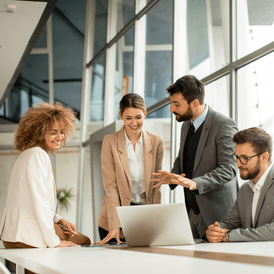 Professionals collaborating around a laptop, ensuring seamless and impactful interactions to maximize business effectiveness.