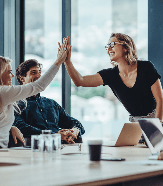 Office colleagues celebrating success with enthusiastic high fives, fostering a positive and collaborative work environment.