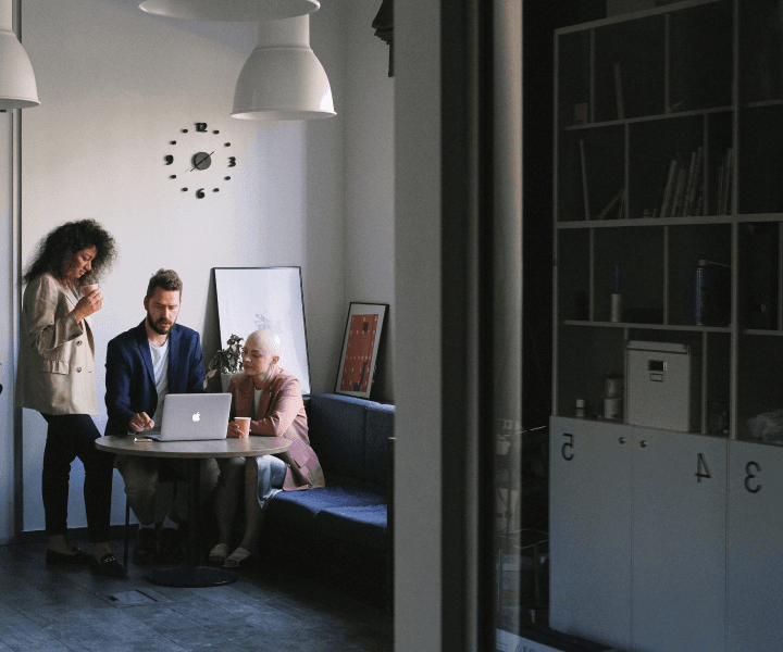 Three professionals strategizing on a laptop at a table, boosting sales efficiency.