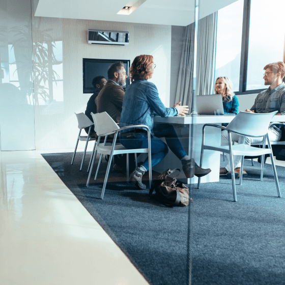 Professionals engaged in a meeting at a conference table, discussing strategies to improve customer satisfaction and loyalty.