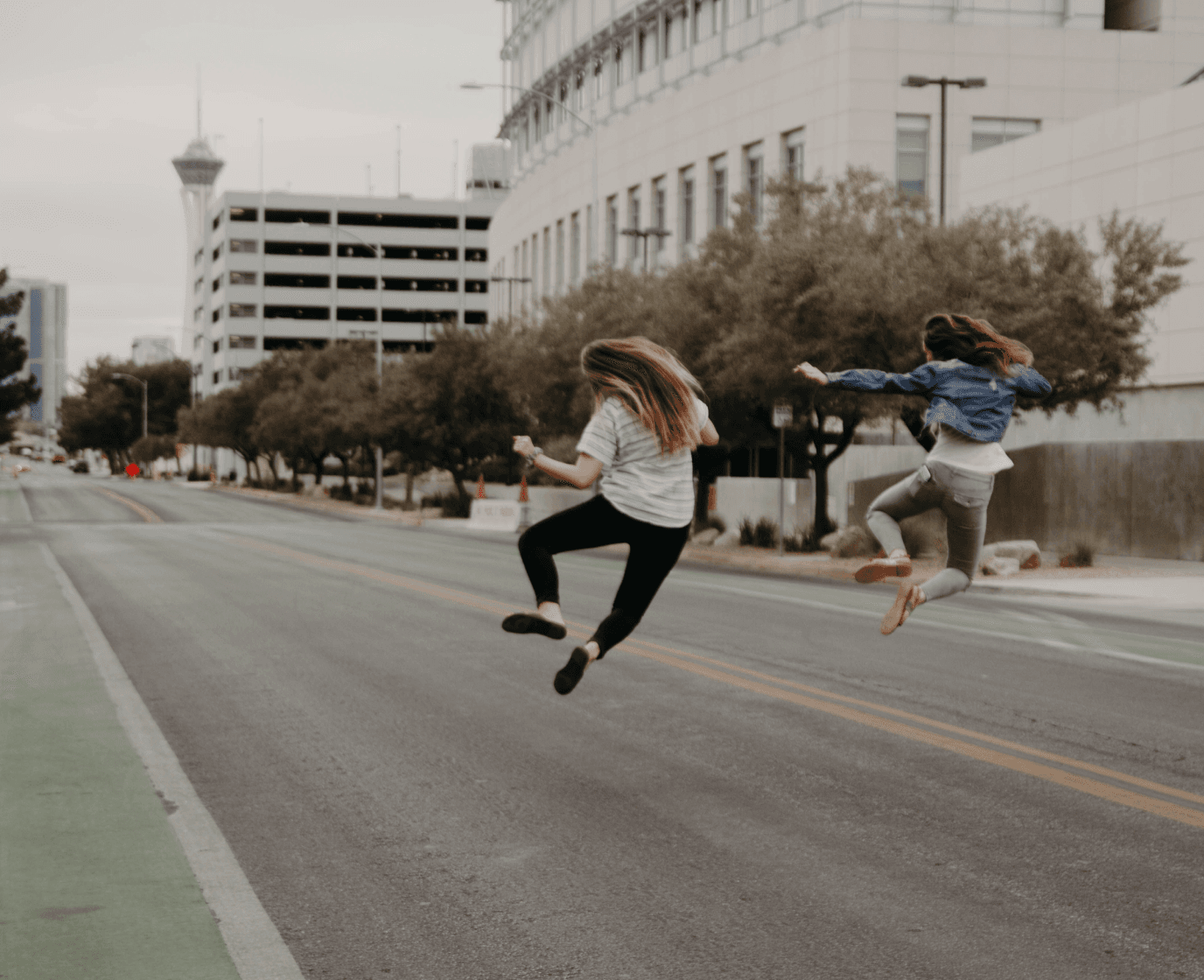 Vibrant image of two women energetically jumping on a street, symbolizing the welcoming and diverse environment at Spiky.