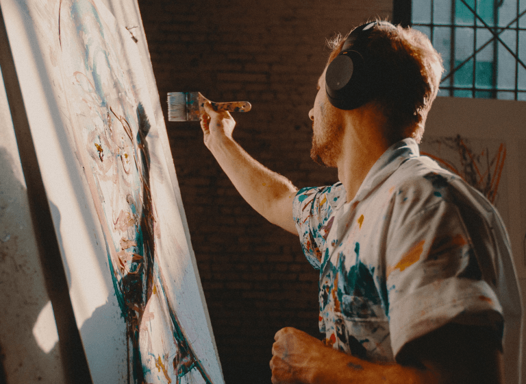 With dedication and expertise, an artist finds fulfillment in an art studio, as he paints on a canvas, merging passion and skill harmoniously.