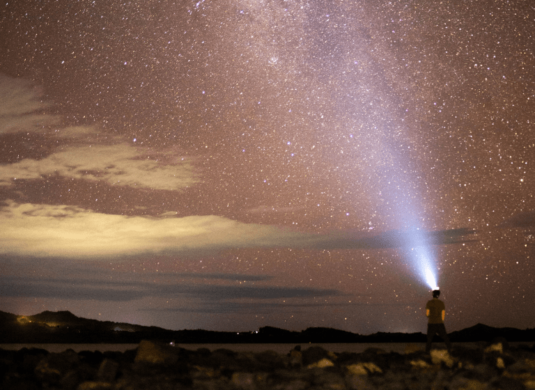 Person on rocks gazes at sky, learns 1% daily for 37x growth in a year. "I will learn" mindset only.