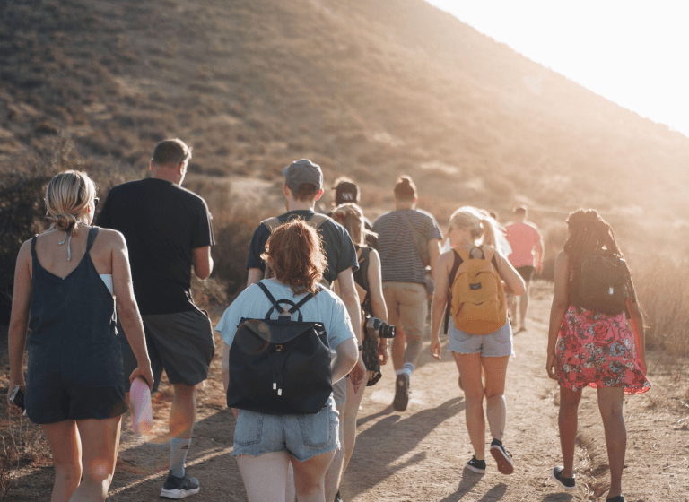 A diverse group of individuals walking along a dusty path, embodying the golden rule of transparency, helpfulness, and respect.